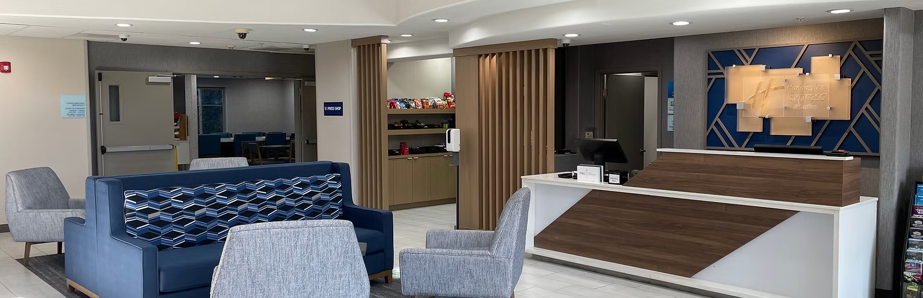 Modern hotel lobby with reception desk, seating area, and decor elements.